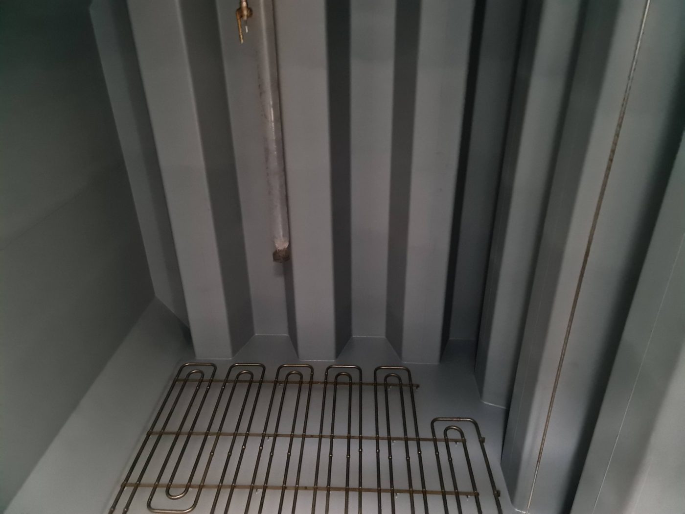 Interior of a coated tank with a smooth grey finish and a heating coil on the floor